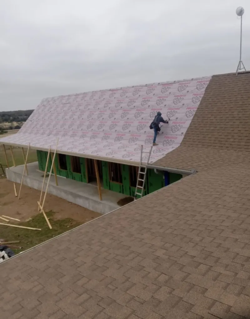 Worker preparing underlayment for a metal roof installation in Ridgefield